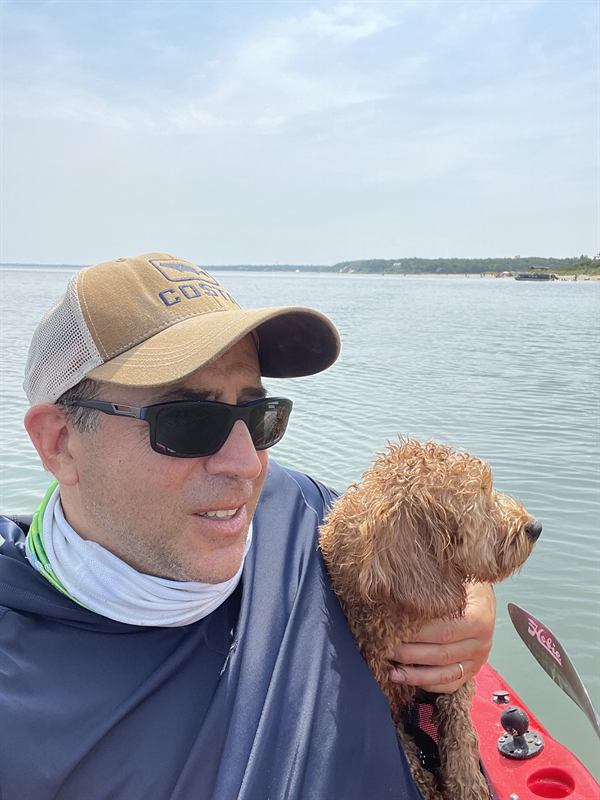 Hobie by the water with a fisherman in a cap and sunglasses