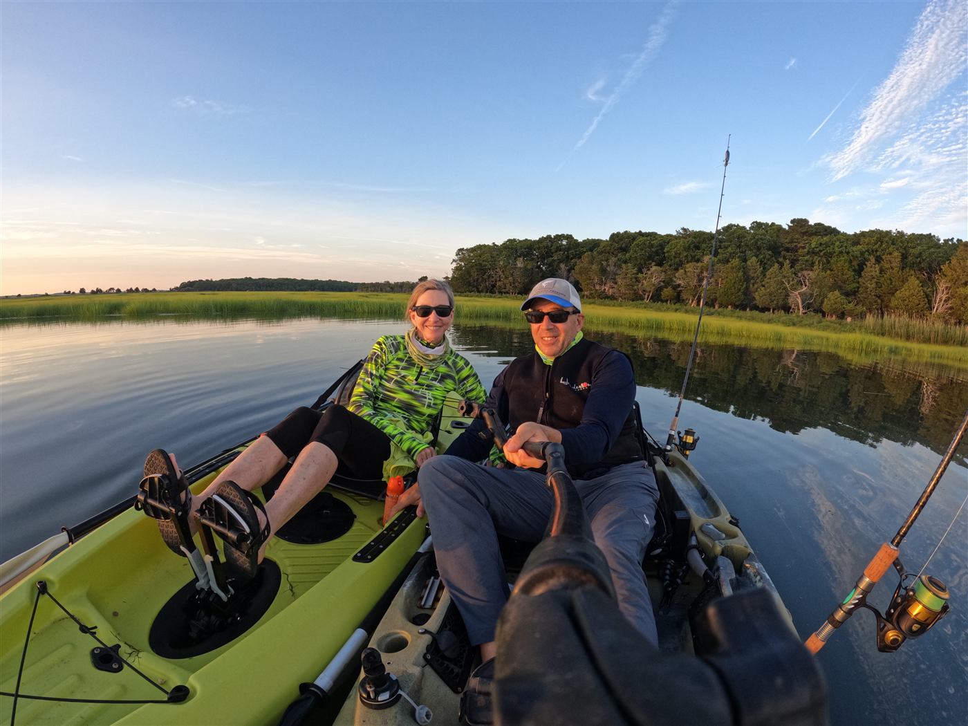 Two kayakers relaxing on calm water in a salt marsh at sunset